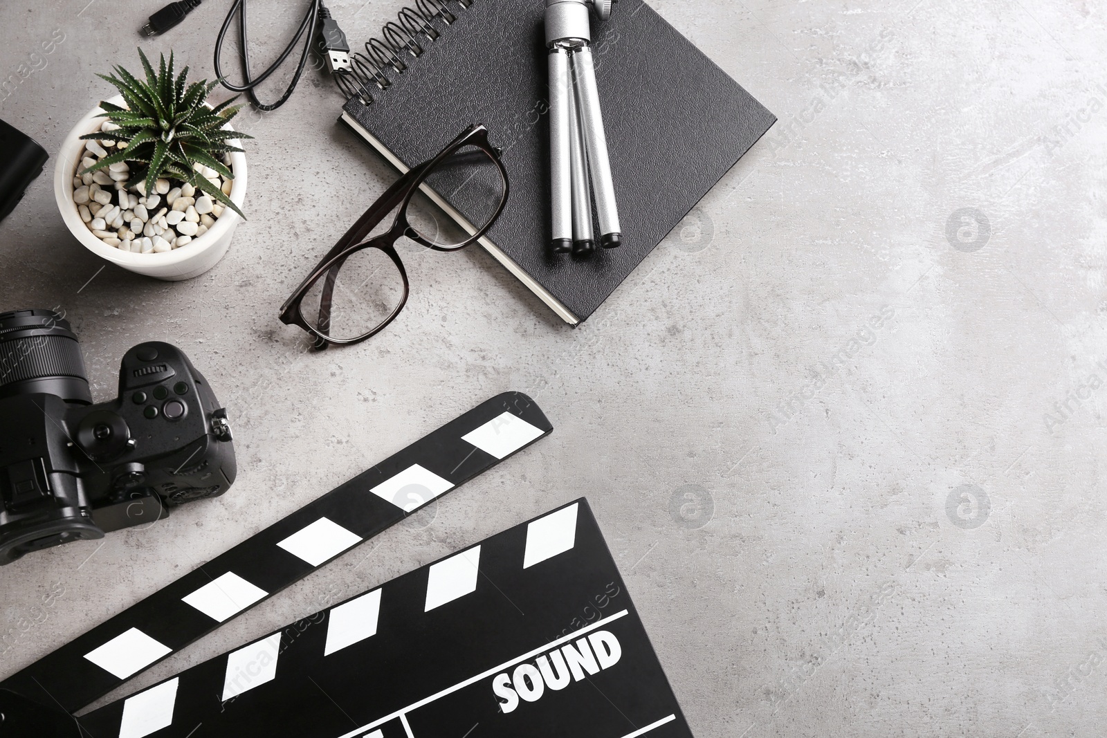 Photo of Flat lay composition with camera on light grey stone table, space for text. Video production industry