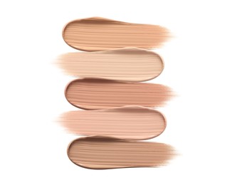 Different shades of liquid skin foundation on white background, top view