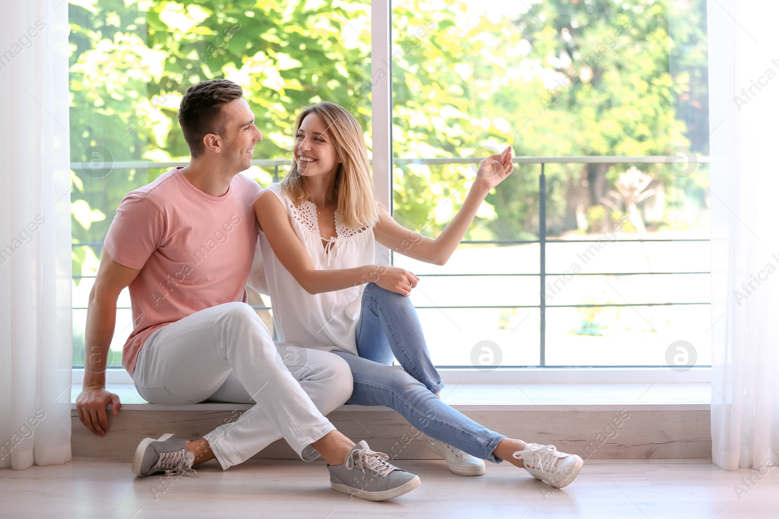 Photo of Happy young couple sitting near window at home
