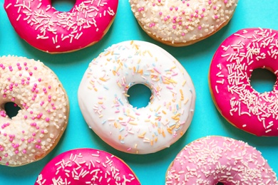 Delicious glazed doughnuts on color background, top view