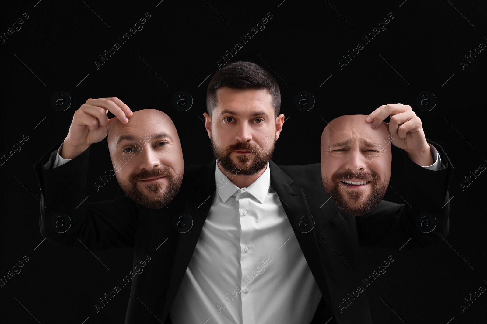 Image of Man holding masks with his face showing different emotions on black background. Balanced personality