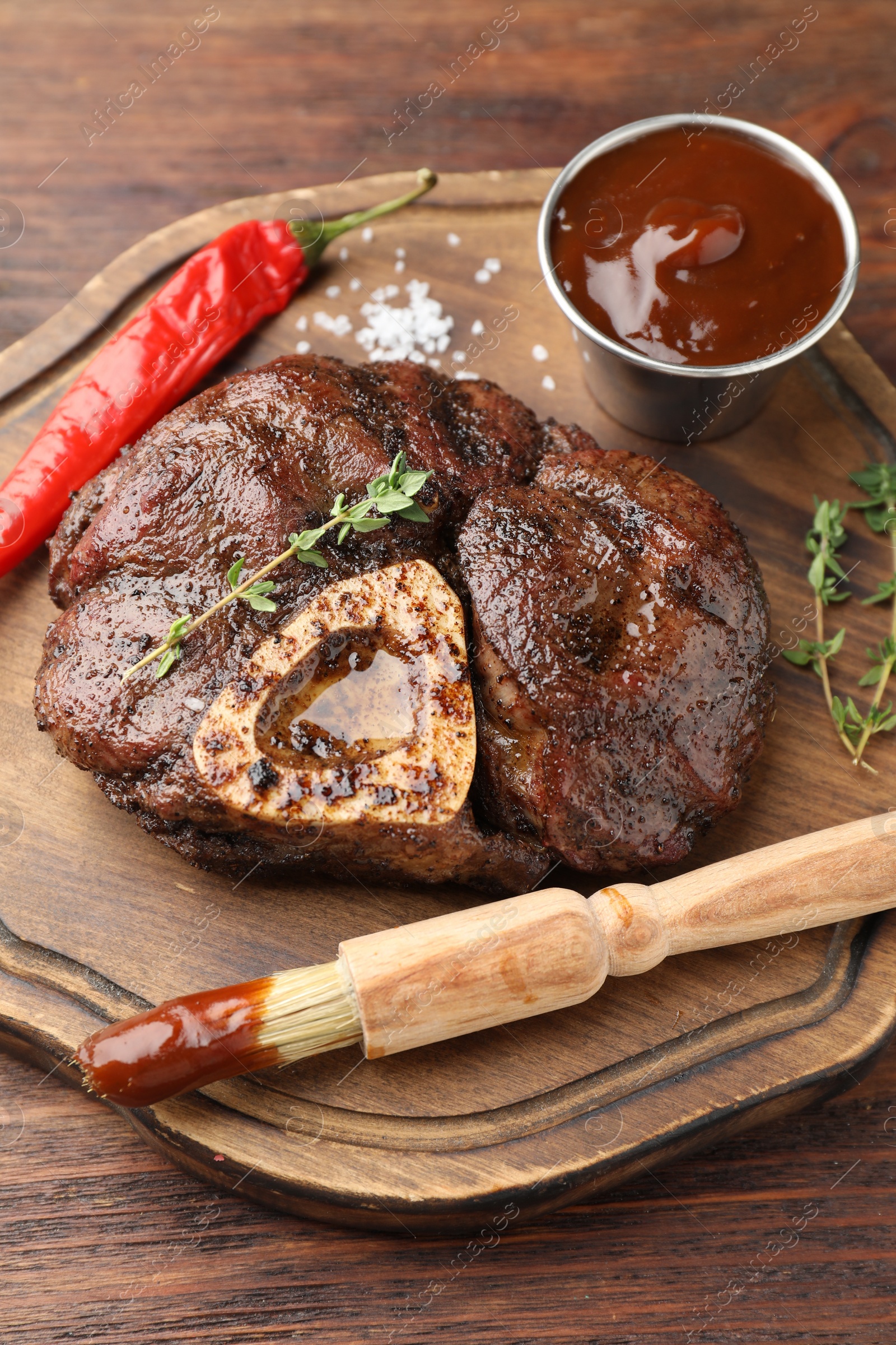 Photo of Delicious roasted beef meat served with sauce and spices on wooden table, closeup