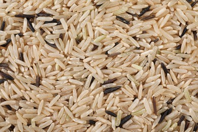 Photo of Raw unpolished rice as background, top view