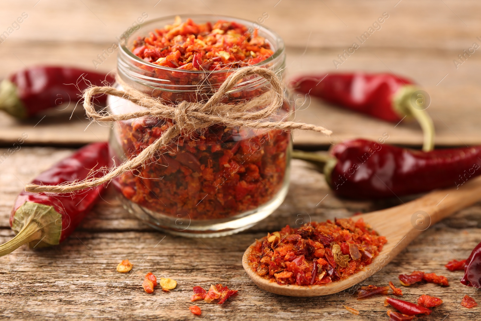 Photo of Chili pepper flakes and pods on wooden table, closeup