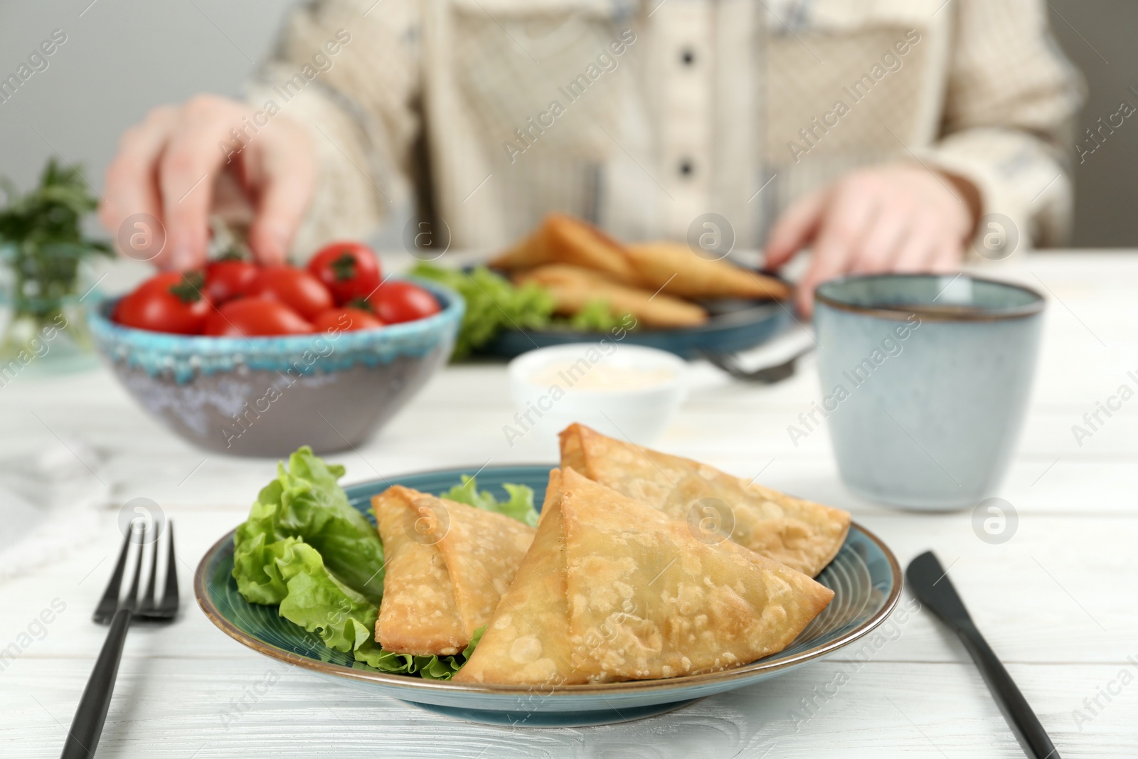 Photo of Delicious samosas served on white wooden table, closeup