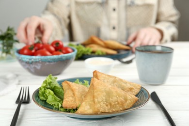 Photo of Delicious samosas served on white wooden table, closeup