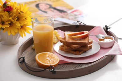 Photo of Wooden tray with delicious breakfast and beautiful flowers on white table