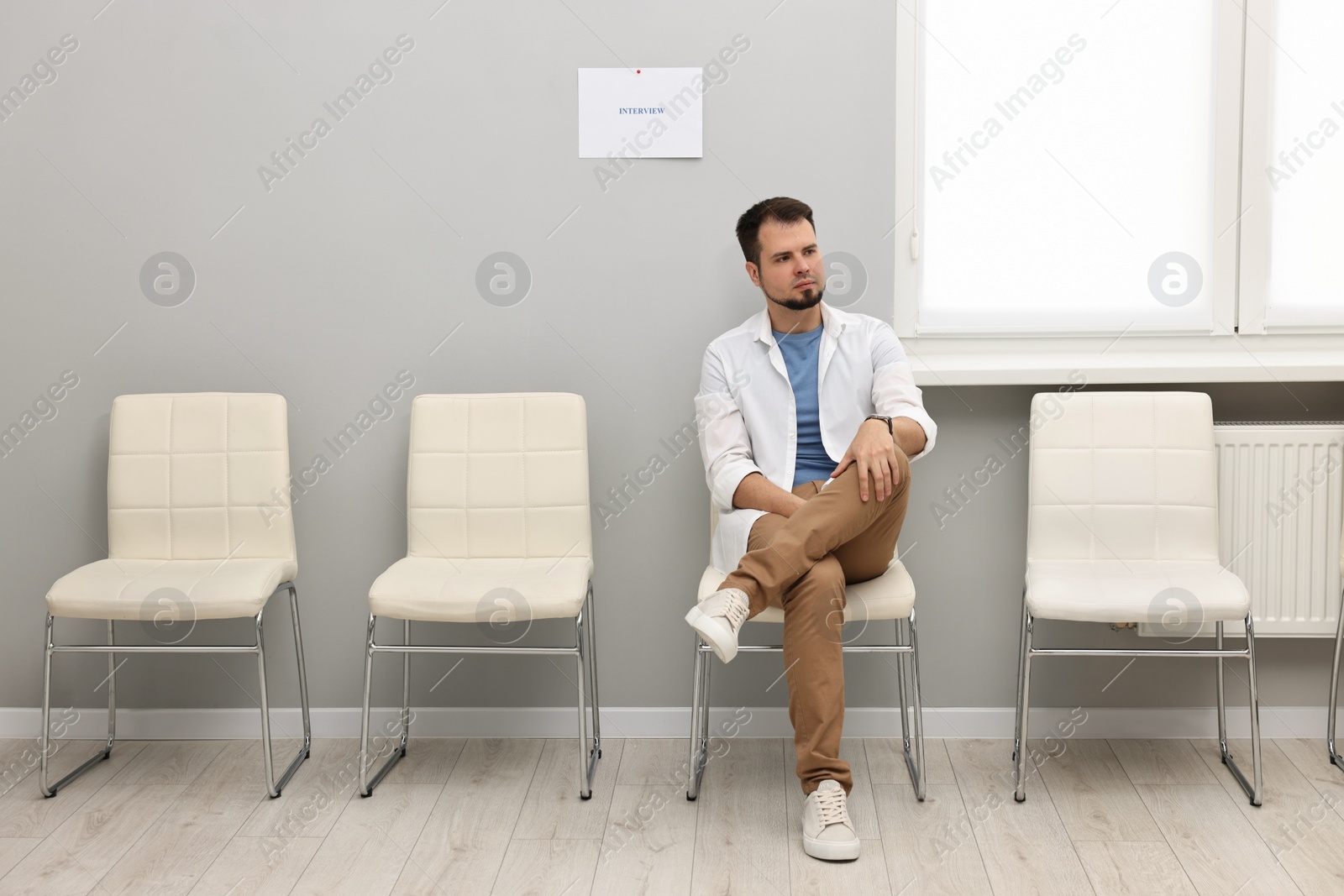 Photo of Man sitting on chair and waiting for job interview indoors