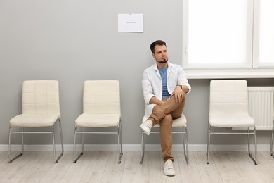 Man sitting on chair and waiting for job interview indoors