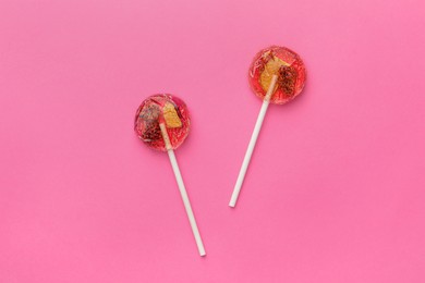 Photo of Sweet colorful lollipops with berries on pink background, flat lay