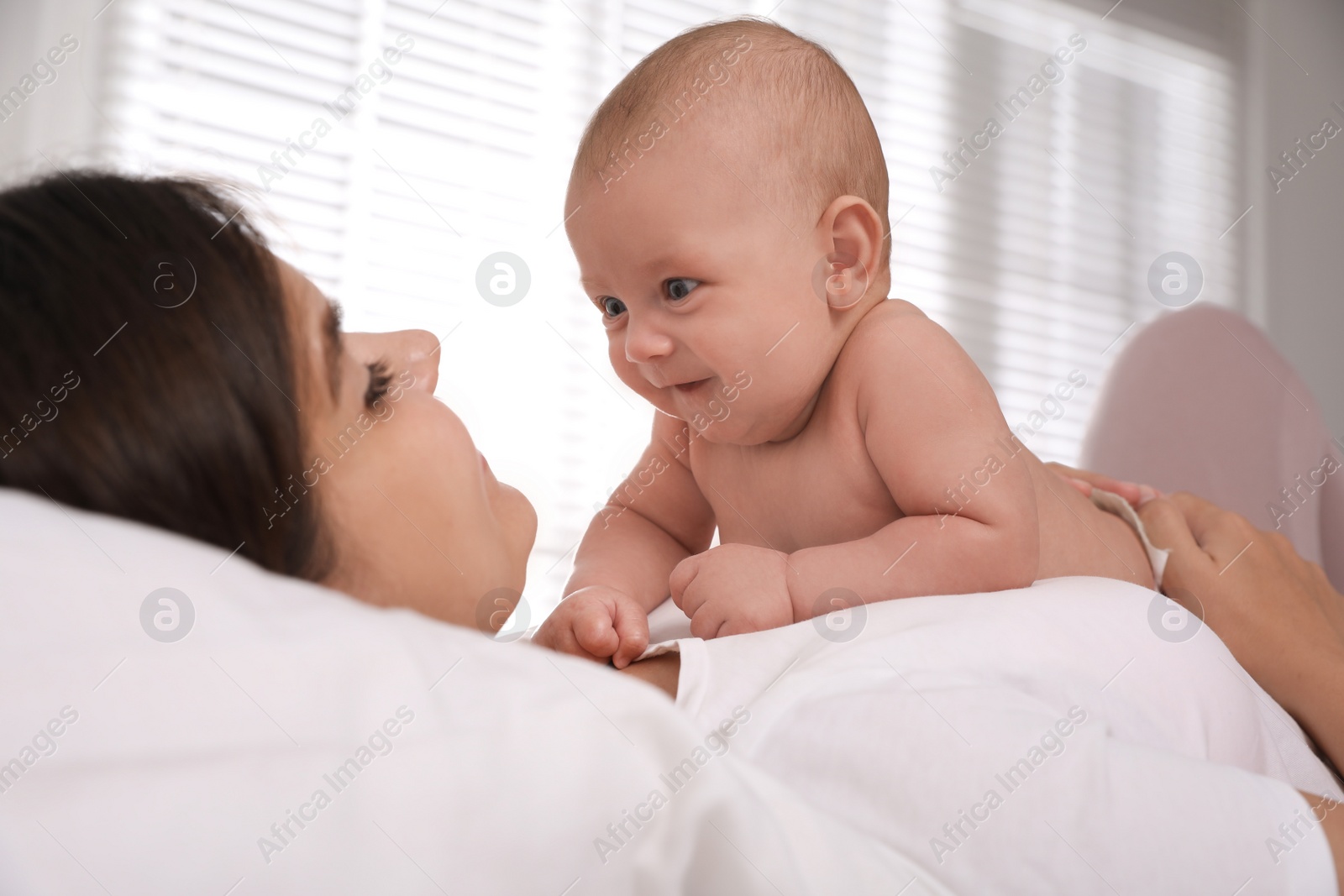 Photo of Young mother with her cute baby on bed at home