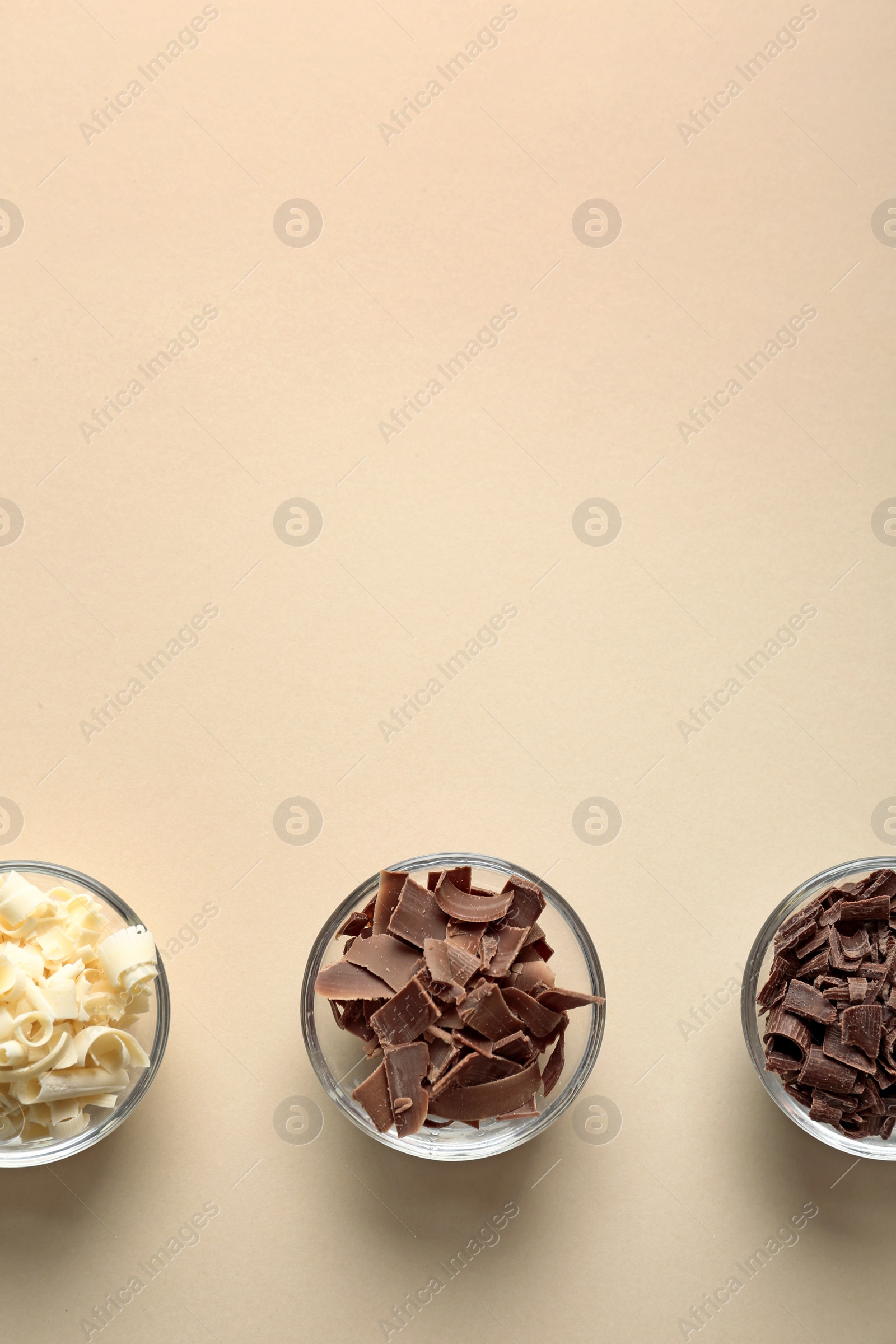 Photo of Bowls with different chocolate curls and space for text on color background, top view
