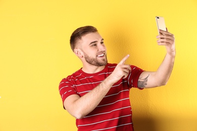Photo of Young man using video chat on smartphone against color background