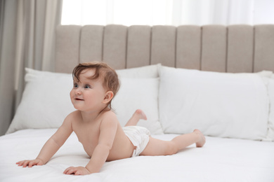 Cute little baby in diaper on bed
