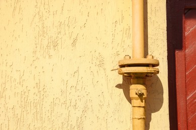 Photo of Yellow gas pipe on beige wall outdoors, space for text