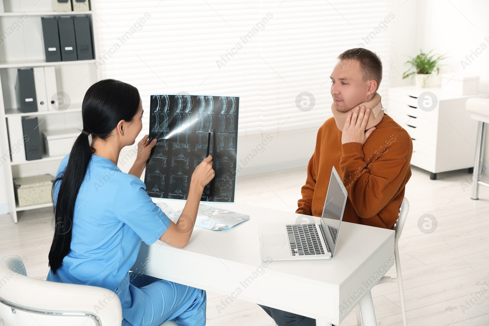 Photo of Doctor with neck MRI image consulting patient in clinic