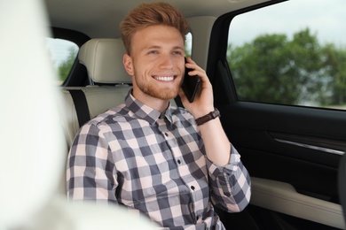 Photo of Attractive young man talking on phone in luxury car