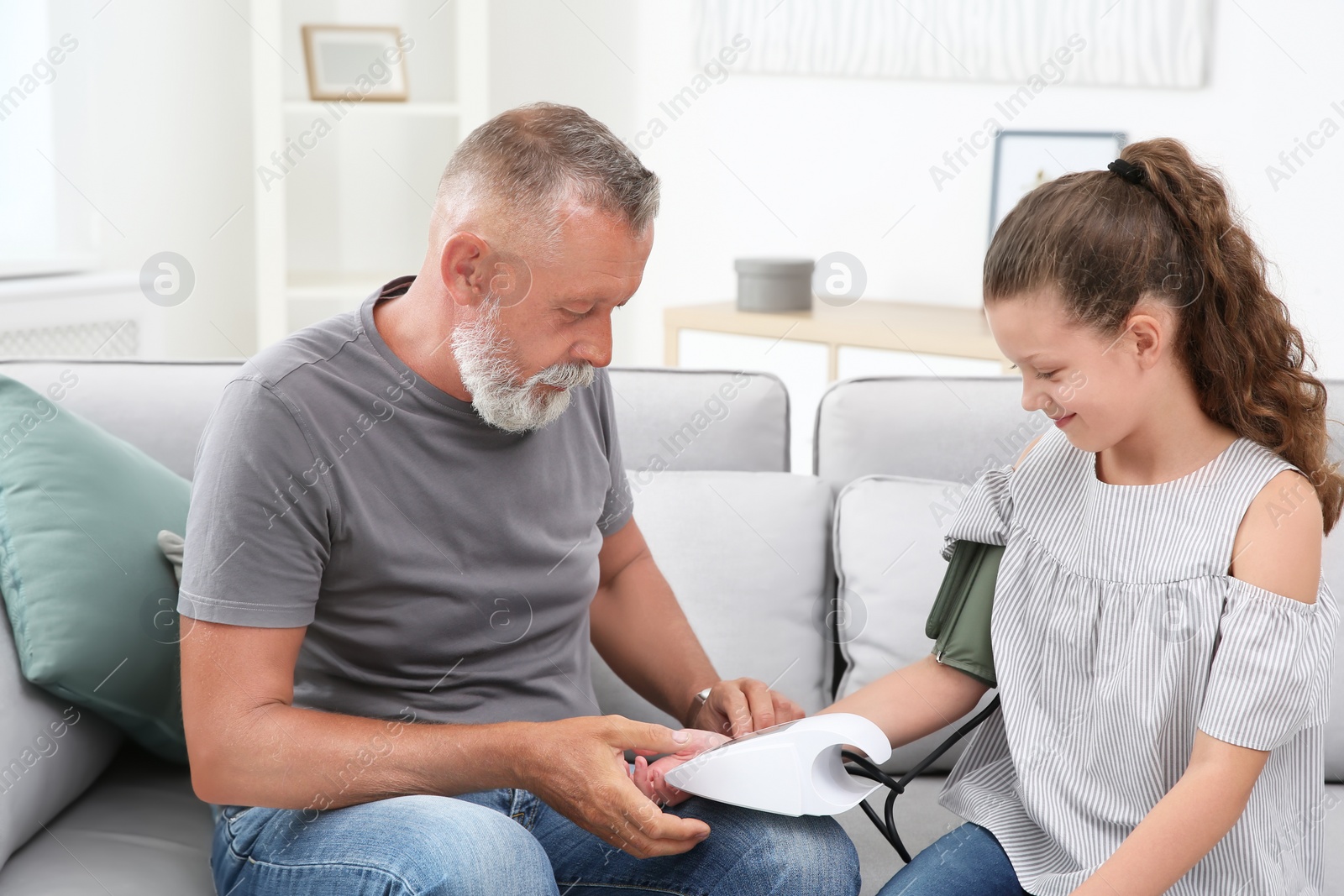 Photo of Senior man checking little girl's pulse indoors