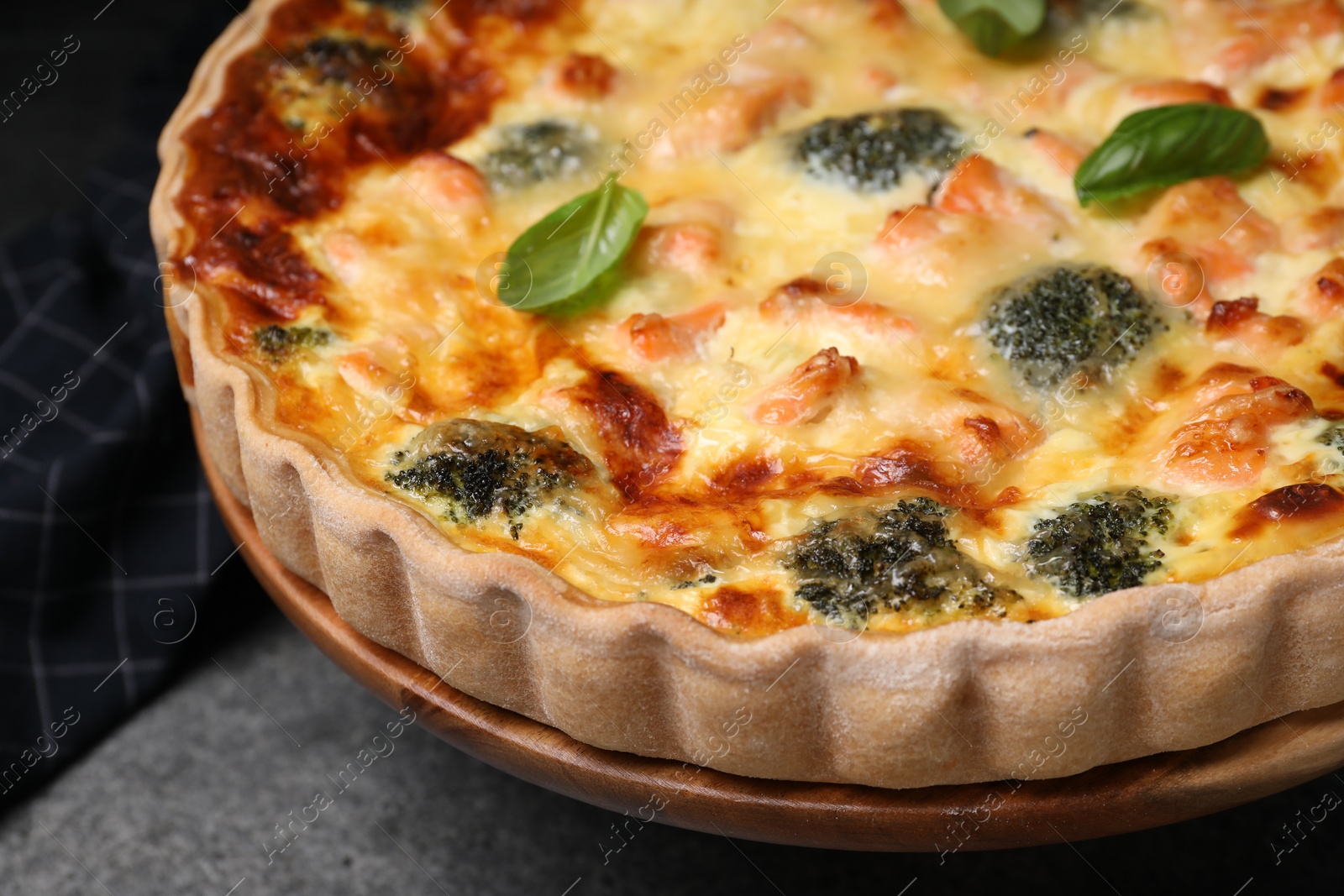 Photo of Delicious homemade quiche with salmon and broccoli on gray table, closeup