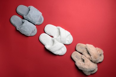 Photo of Different soft fluffy slippers on red background, flat lay