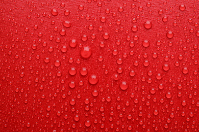 Photo of Water drops on red background, top view