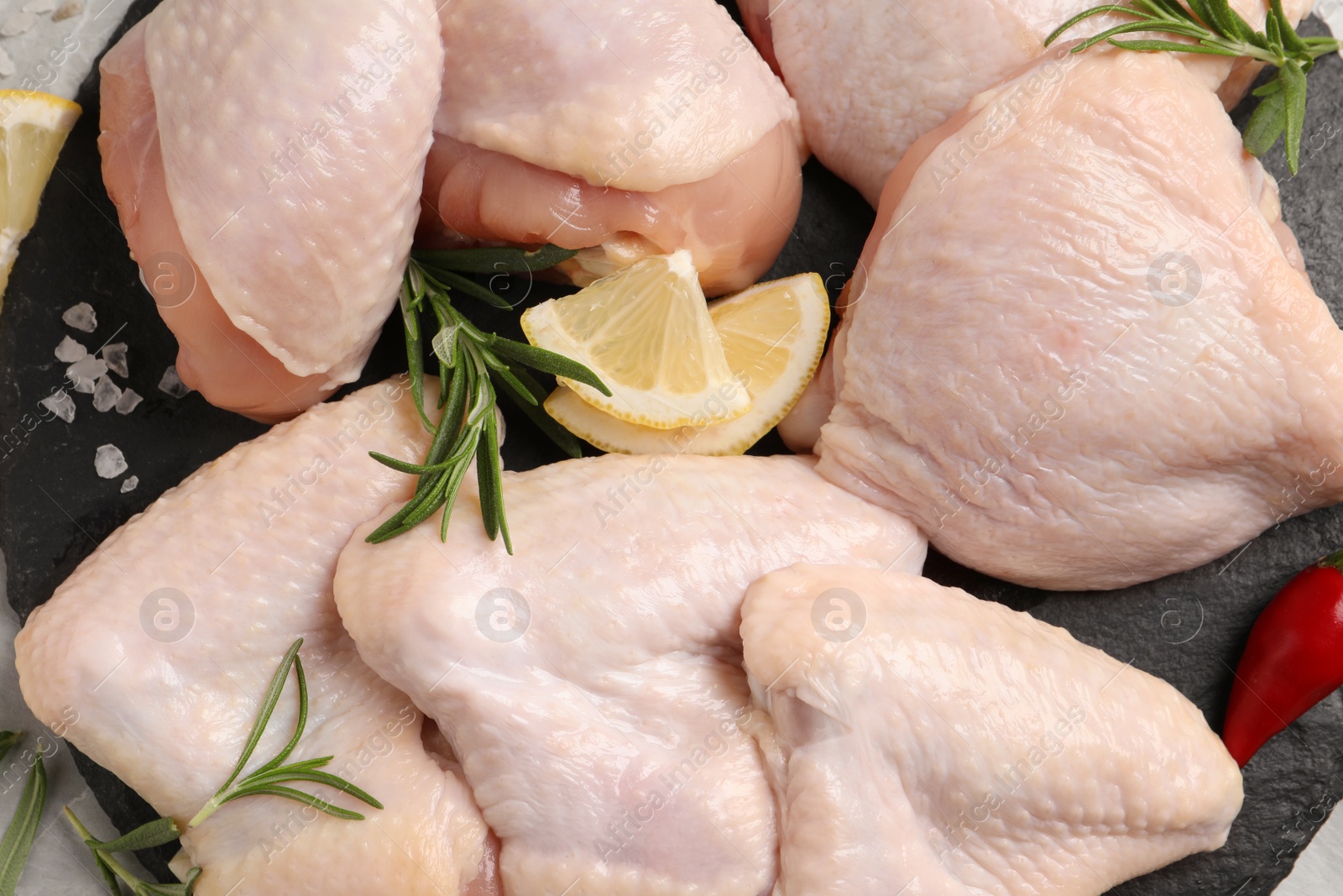 Photo of Fresh raw chicken meat and other products on slate board, top view