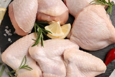 Fresh raw chicken meat and other products on slate board, top view