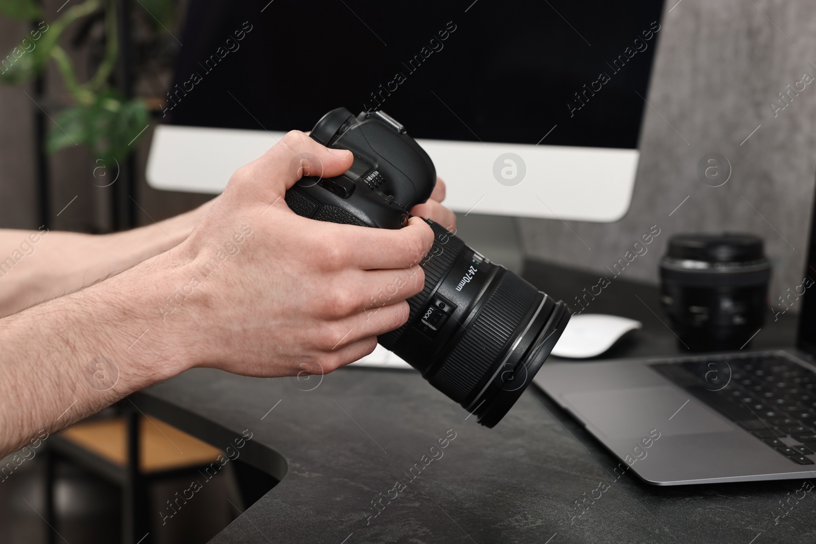 Photo of Photographer holding camera at dark table, closeup