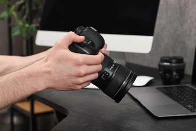 Photographer holding camera at dark table, closeup