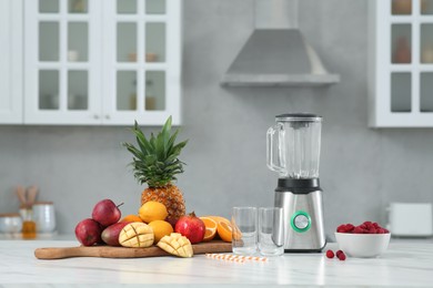 Photo of Blender and smoothie ingredients on white marble table in kitchen