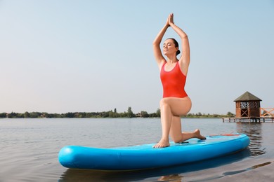 Photo of Woman practicing yoga on light blue SUP board on river, space for text
