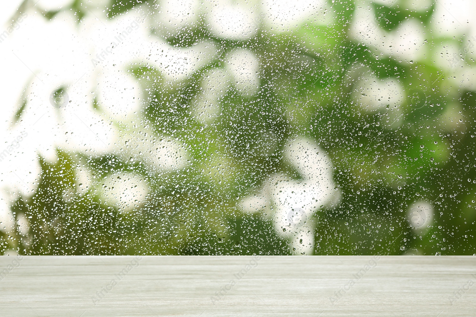 Image of White wooden table near window on rainy day