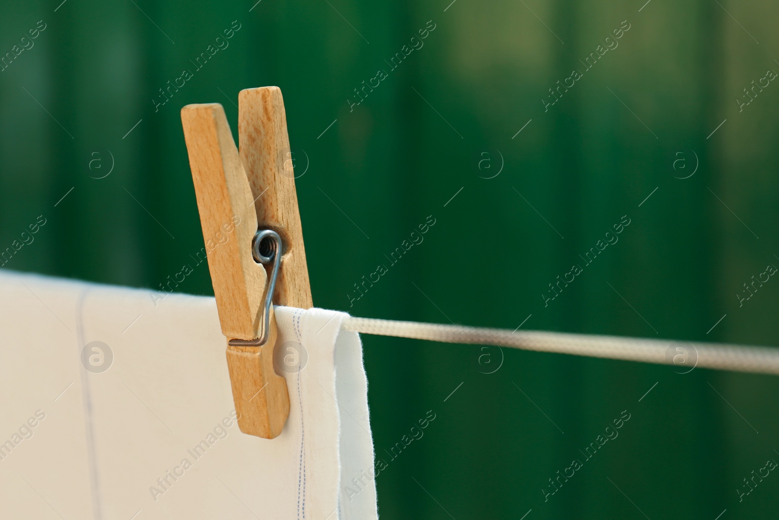 Photo of Washing line with clean laundry and clothespin outdoors, closeup