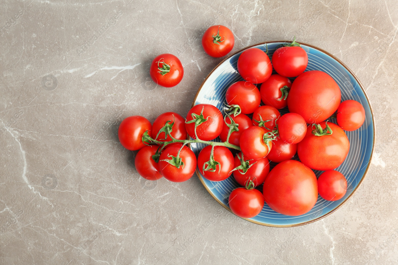 Photo of Plate with fresh ripe tomatoes on grey background, top view