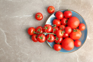 Photo of Plate with fresh ripe tomatoes on grey background, top view