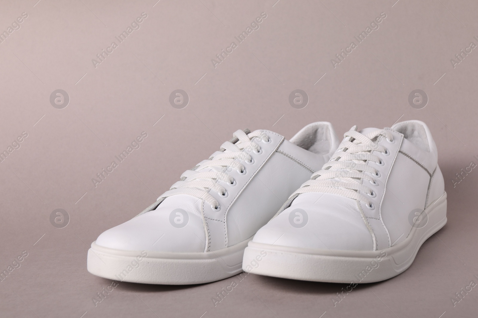 Photo of Pair of stylish white sneakers on grey background