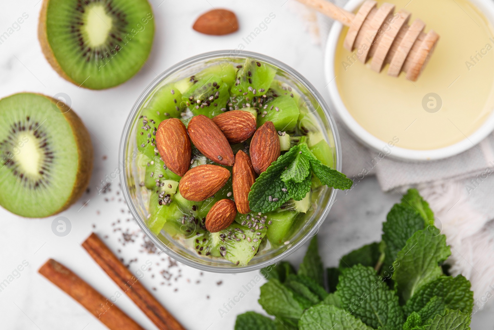 Photo of Delicious dessert with kiwi, almonds and mint on white table, flat lay