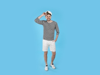 Photo of Happy sailor wearing cap on light blue background