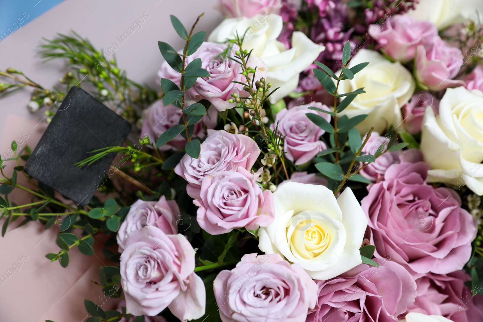 Photo of Beautiful fresh roses with price tag, closeup. Floral shop