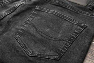 Photo of Black jeans with pocket on wooden background, closeup