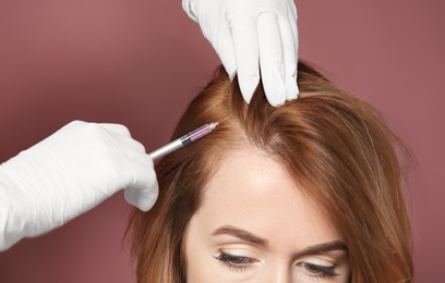 Photo of Young woman with hair loss problem receiving injection, on color background