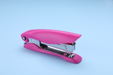 New bright stapler on light blue background. School stationery