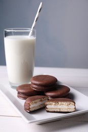 Tasty choco pies and milk on white wooden table
