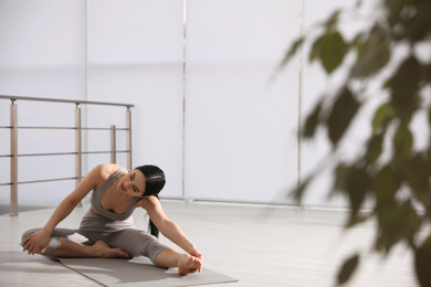 Photo of Young woman stretching leg in yoga studio. Janu Sirsasana pose variation