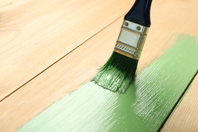 Photo of Applying green paint onto wooden surface, closeup. Space for text