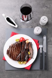 Delicious grilled beef meat served on grey table, flat lay