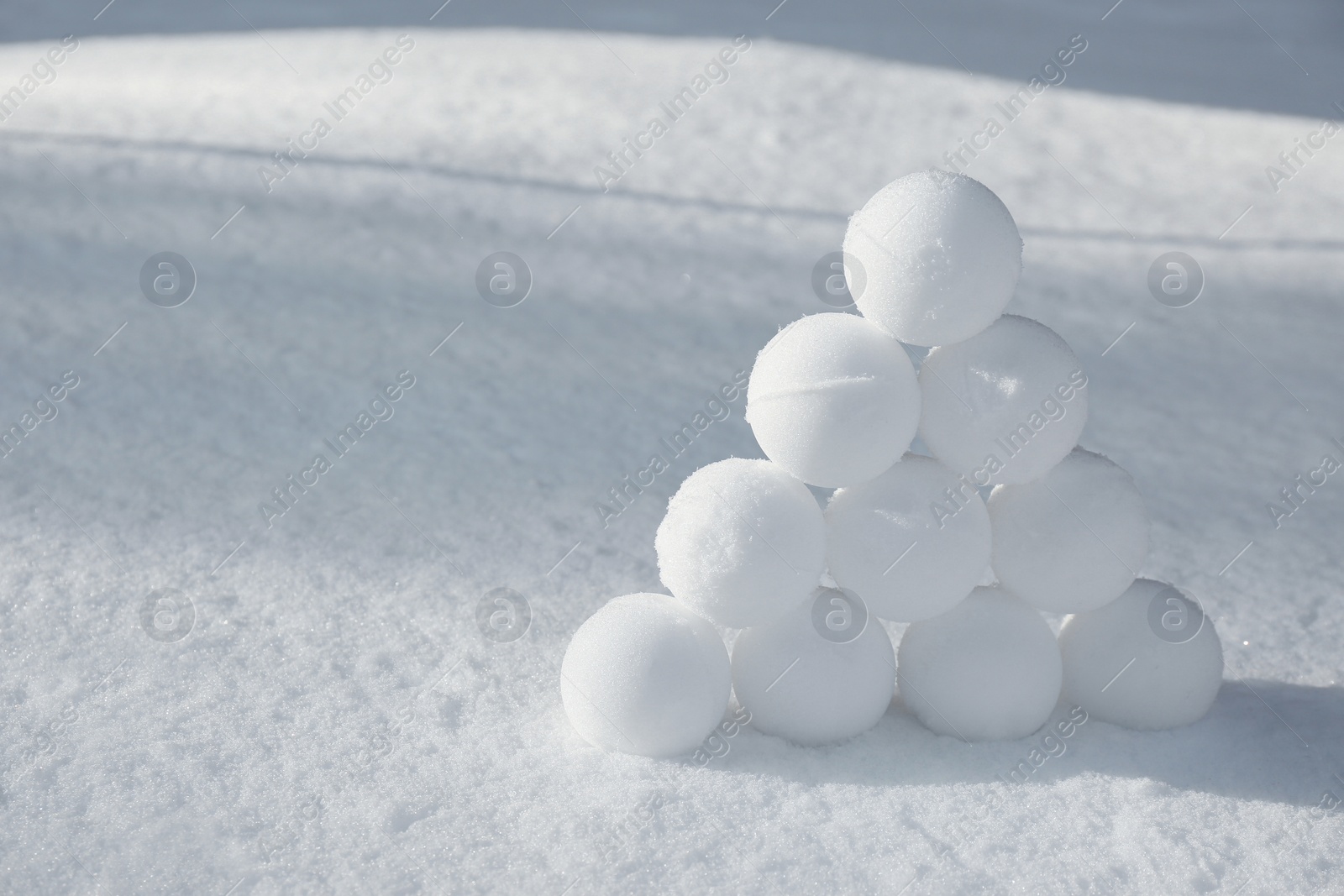 Photo of Pyramid of perfect snowballs on snow outdoors. Space for text