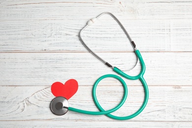 Photo of Stethoscope and red heart on wooden background, top view. Cardiology concept