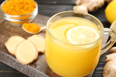 Photo of Immunity boosting drink with ginger, lemon and turmeric on table, closeup
