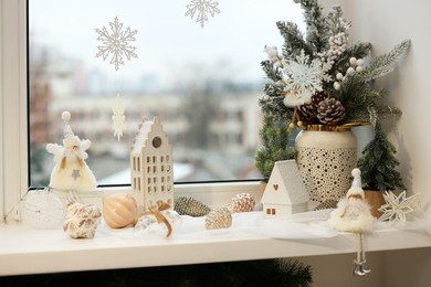 Many beautiful Christmas decorations and fir branches on window sill indoors